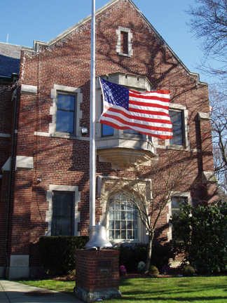 A flag is flying at half-mast outside a building, symbolizing mourning or respect for a significant event.